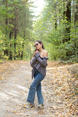 Fototapeta premium Portrait of romantic woman at fairy forest. A beautiful young girl with glasses is walking through the forest. Girl purple suit. Corduroy fabric