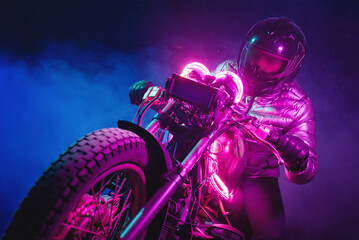 Naklejka na ściany i meble A futuristic motorbiker on the neon light motorcycle close up.