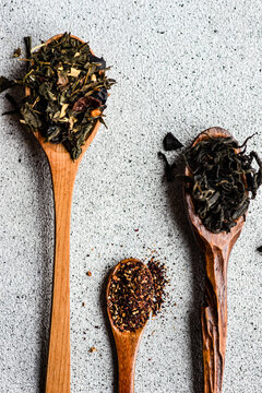 Overhead view of three wooden spoons with assorted teas on a table