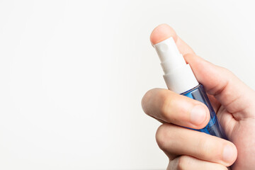 holding a small blue spray bottle on white background with space for text.
