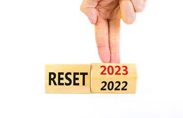 2023 reset new year symbol. Businessman turns a wooden cube and changes words Reset 2022 to Reset 2023. Beautiful white table white background, copy space. Business 2023 reset new year concept.