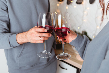 Lovely young couple sitting floor kitchen drink wine in glasses, garlands home cosy interior atmosphere New Year Christmas tree decorations holiday party celebrating concept winter evening 
