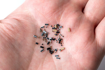 Human hand with various micro electronic elements on white background.