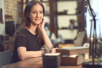 Successful confident businesswoman working, using laptop computer, looking at camera.