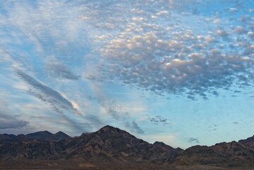 Illuminated altocumulus clouds at sunset over badlands in Death Valley National Park - obrazy, fototapety, plakaty