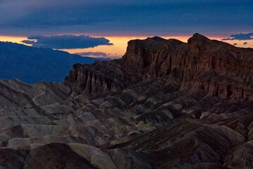 Twilight at Zabriskie Point as sun sets on horizon under cloud cover