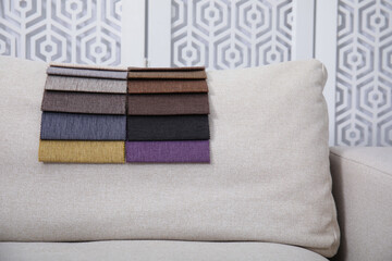 Catalog of colorful fabric samples on beige sofa indoors