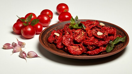 Dried tomatoes with basil garlic and spices in a clay bowl close-up on a white background