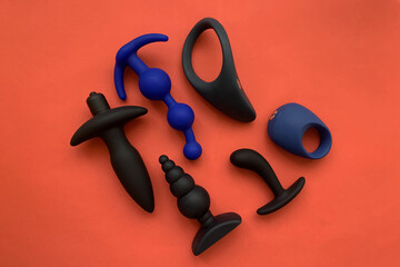 Sex shop assortment. Black sex toys. cock ring, butt plags and prostate massager. Red background