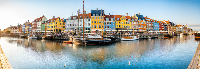 Panoramablick auf Nyhawn, die bunten Häuser neben dem alten Hafen. Touristen, die in der Abenddämmerung Restaurants, Cafés und Schiffe im Kanal besuchen. Die wichtigste Sehenswürdigkeit in Kopenhagen, Dänemark.