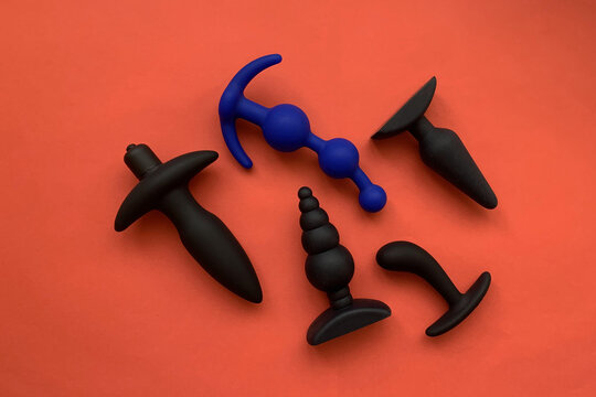 Black sex toys. Five butt plugs on red background. Useful for sex shop