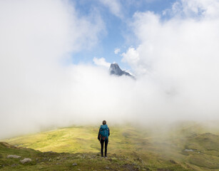 Girl with backpack hiking, Midi d?Ossau peak in the background in the Pyrenees National Park, France.