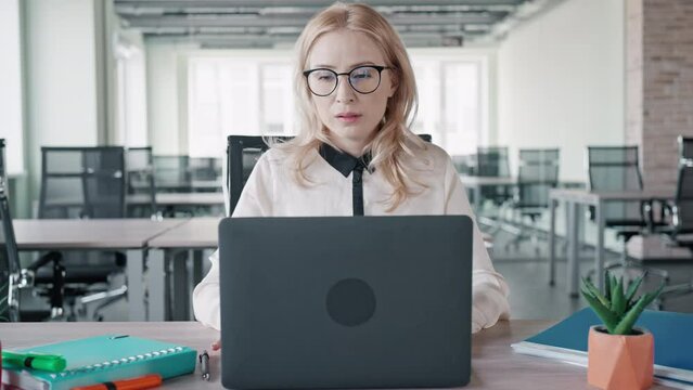 overworked manager at workplace turn of computer looking camera sitting at the desk in the office