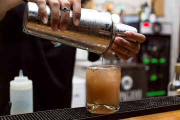 Bartender serving alcohol in a cocktail. Cocktail preparation in a night environment. It can be a hotel, a restaurant or a night club.