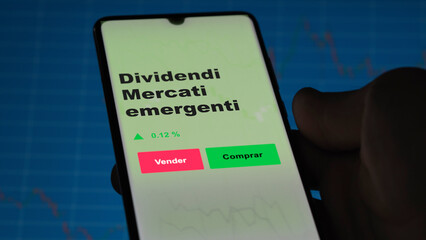 Un inversor está analizando el dividendi mercati emergenti etf fondo en pantalla. Un teléfono muestra los precios del ETF para invertir.