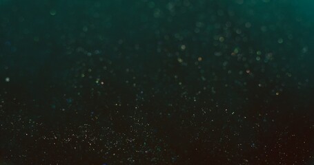 Particles background. Bokeh sparks texture. Blur glitter. Defocused teal blue golden shiny sparkles on dark color gradient abstract wallpaper.