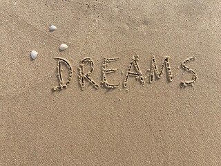on the beach is carved with letters in the smooth sand the writing Dreams