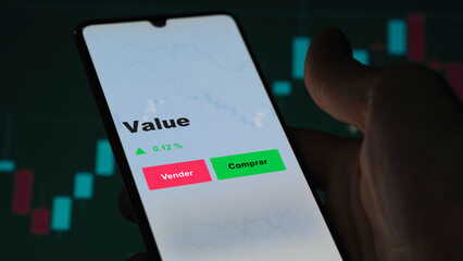 Un inversor está analizando el value etf fondo en pantalla. Un teléfono muestra los precios del ETF para invertir. Texto en español.