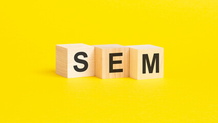 wooden blocks with text SEM on yellow background. business concept