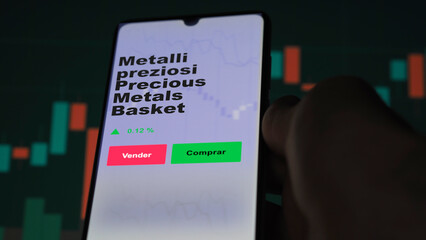 Un inversor está analizando el metalli preziosi precious metals basket etf fondo en pantalla. Un teléfono muestra los precios del ETF para invertir. Texto en español.