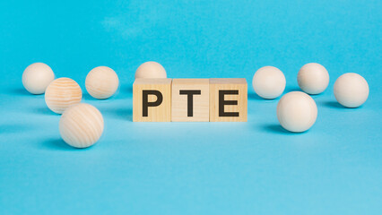 business concept. on the blue table wooden balls and wooden cubes with the inscription - PTE - Pearson Tests of English