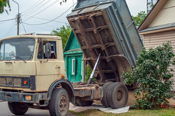 Obraz premium Dump trucks carrying good filling a field, giving rise to a fine soil. Preparation and construction.