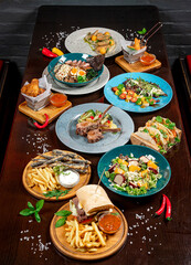 Different colorful meals on dark wooden table in the restaurant.