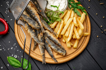 Small fried fish and french fries at an seaside restaurant. Fried anchovies