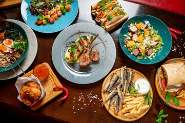 Different colorful meals on dark wooden table in the restaurant.