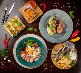 Different colorful meals on dark wooden table in the restaurant.