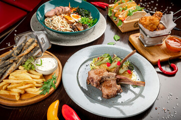 Different colorful meals on dark wooden table in the restaurant.