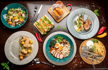 Different colorful meals on dark wooden table in the restaurant.
