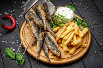 Small fried fish and french fries at an seaside restaurant. Fried anchovies
