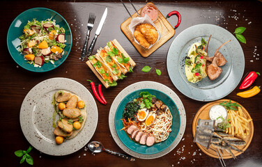 Different colorful meals on dark wooden table in the restaurant.