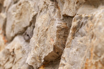 Old rough stone wall with weathered abstract cracked texture