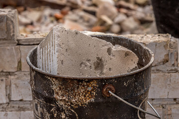 Stone dump on the ruins of a private house. A pile of construction debris and stones. Remains of bricks in a bucket.