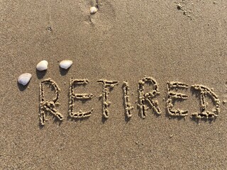 on the beach is carved with letters in the smooth sand the writing Retired