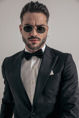sexy businessman in tux with sunglasses being confident and posing