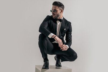 handsome bearded businessman holding elbows on knees and crouching