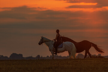 silhouette of a young woman riding a horse