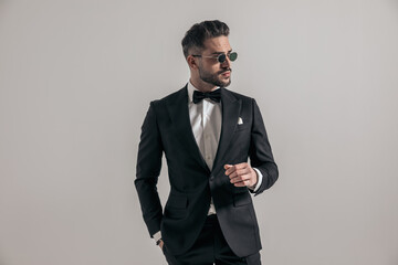elegant businessman in tuxedo with hand in pocket looking to side