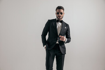 sexy bearded businessman wearing black tuxedo and holding hand in pocket