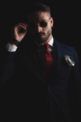 cut out picture of elegant guy in suit with tie and handkerchief adjusting sunglasses