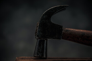 close up image of old rusty carpentry hammer on top of wooden bench