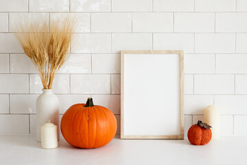 Cozy home interior with frame mockup, autumn fall decorations, pumpkins, vase of wheat, candle....