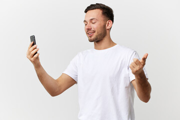 Cheerful smiling tanned handsome man in basic t-shirt talk by video call with friends posing isolated on over white studio background. Copy space Banner Mockup. Distance online communication concept