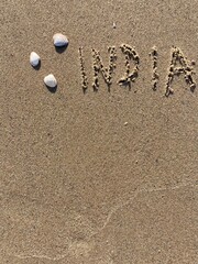 Fototapeta na wymiar on the beach is carved with letters in the smooth sand the writing India
