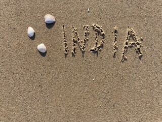 Fototapeta na wymiar on the beach is carved with letters in the smooth sand the writing India