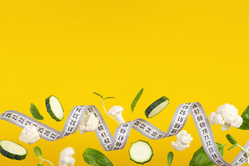 White measuring tape with pieces of vegetables and herbs on a yellow background