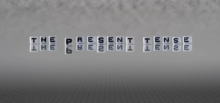 the present tense word or concept represented by black and white letter cubes on a grey horizon background stretching to infinity